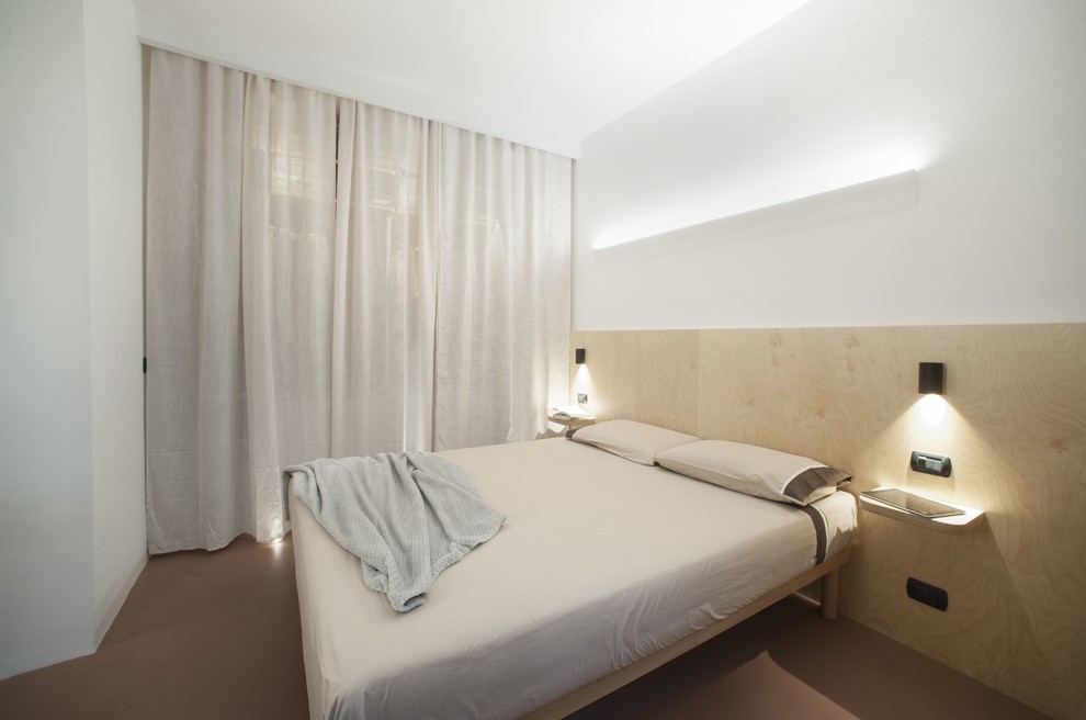 Ejemplo de dormitorio principal moderno pequeño con paredes blancas, suelo de cemento y suelo rojo
