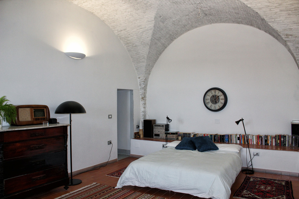 Foto di una camera da letto stile loft contemporanea di medie dimensioni con pareti bianche, pavimento in terracotta e pavimento rosso