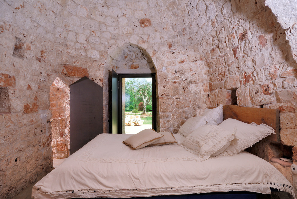 На фото: хозяйская спальня среднего размера в средиземноморском стиле с бежевыми стенами, бетонным полом и серым полом с