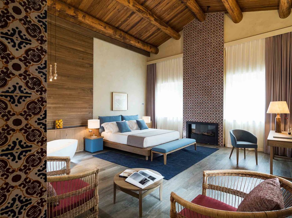 Mediterranes Hauptschlafzimmer mit dunklem Holzboden, brauner Wandfarbe, Kamin, gefliester Kaminumrandung und braunem Boden in Sonstige