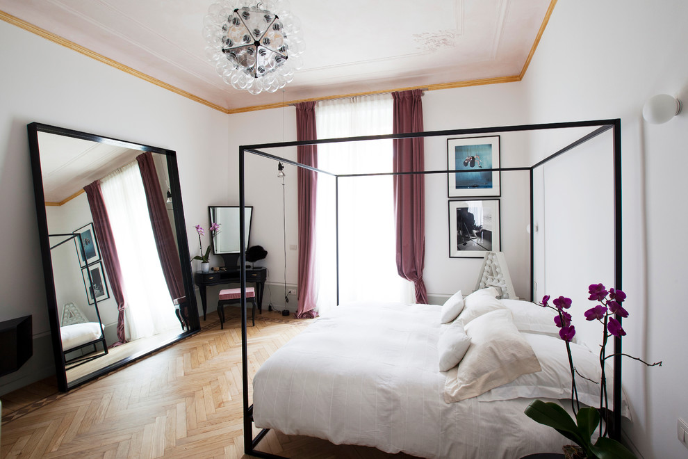 This is an example of a contemporary bedroom in Milan with white walls, medium hardwood flooring and no fireplace.