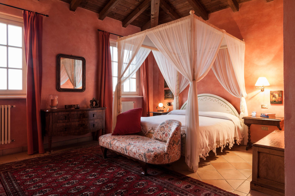 Large farmhouse master bedroom in Milan with red walls and terracotta flooring.