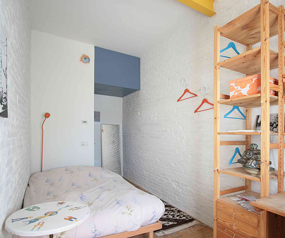 Mittelgroßes Industrial Gästezimmer mit weißer Wandfarbe und braunem Holzboden in Sonstige