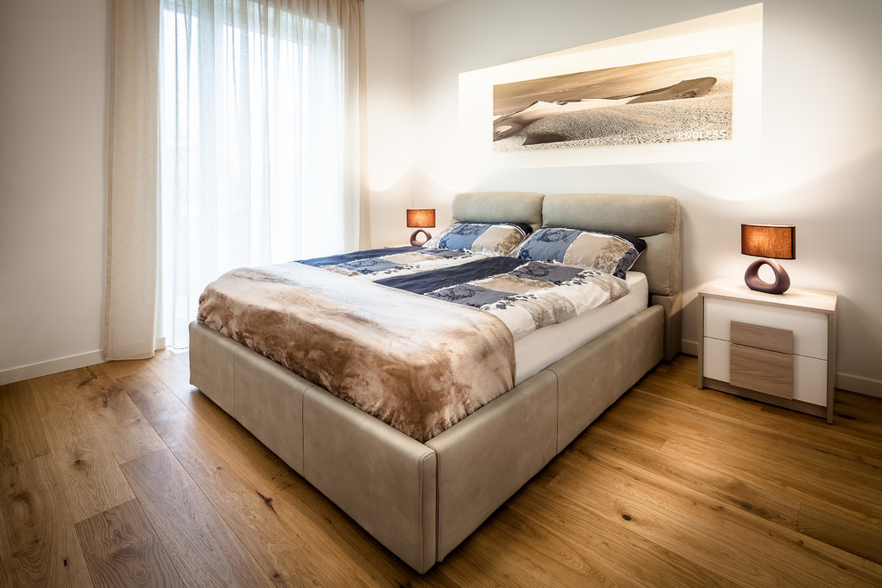 Diseño de dormitorio principal contemporáneo con paredes blancas y suelo de madera en tonos medios