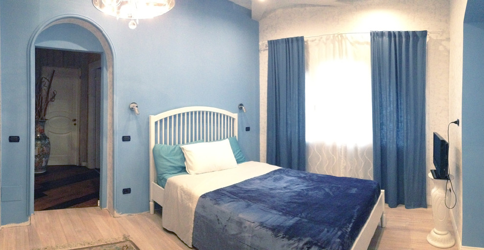 Cette photo montre une petite chambre parentale moderne avec un mur bleu et parquet clair.