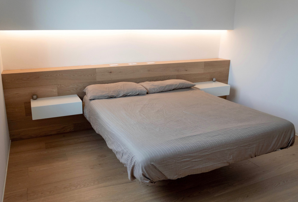 Diseño de dormitorio principal contemporáneo de tamaño medio sin chimenea con paredes blancas, suelo de madera clara y suelo marrón