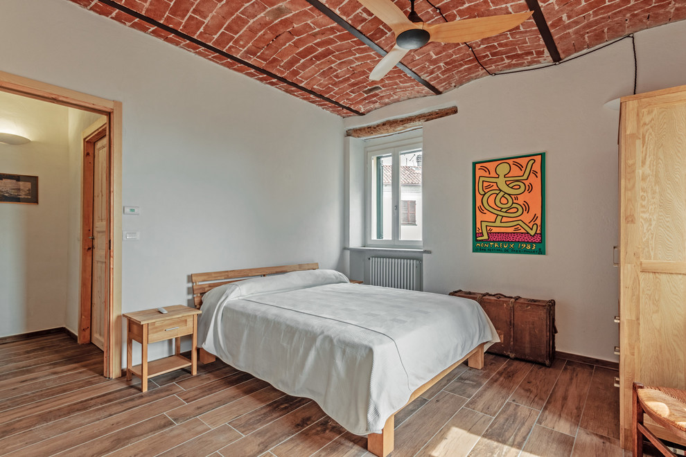 Ejemplo de dormitorio mediterráneo con paredes blancas y suelo marrón