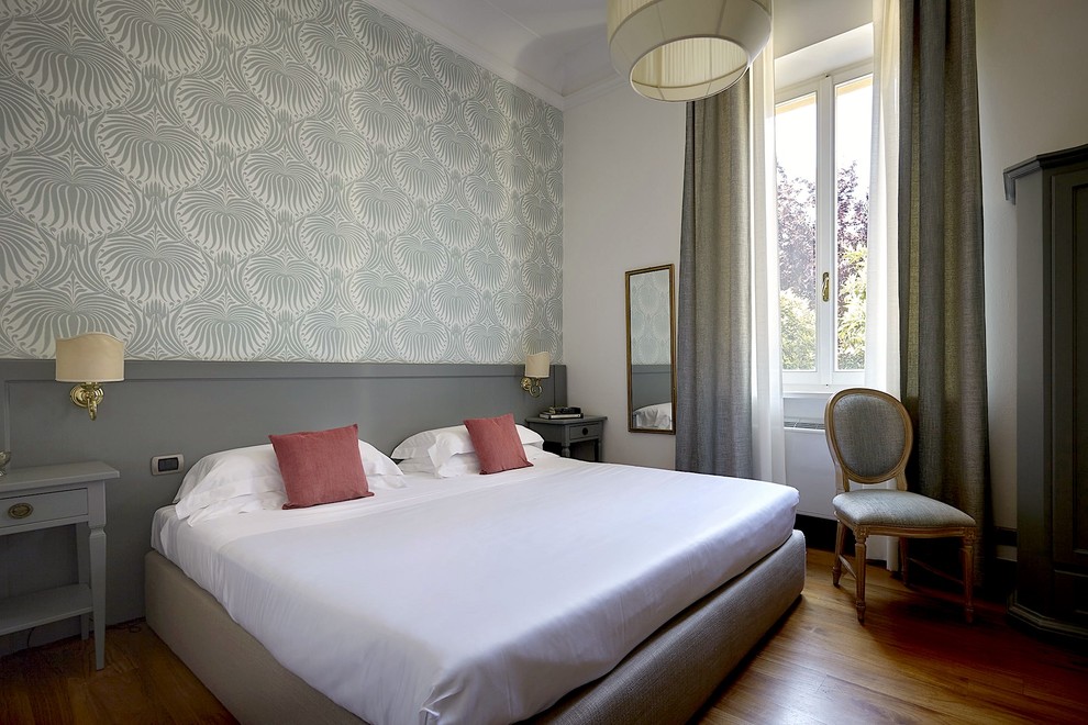 Mittelgroßes Retro Gästezimmer mit grauer Wandfarbe, gebeiztem Holzboden und braunem Boden in Florenz