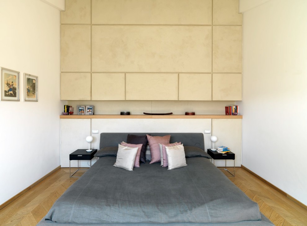 Kleines Modernes Hauptschlafzimmer mit beiger Wandfarbe, hellem Holzboden und braunem Boden in Mailand