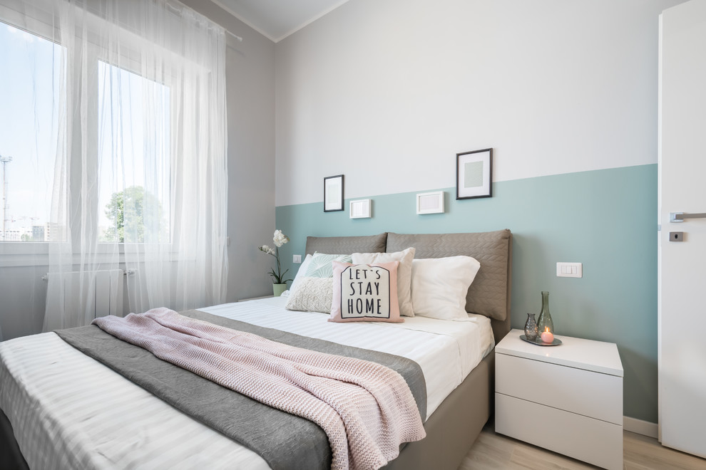 Small scandi master bedroom in Milan with beige walls, light hardwood flooring and beige floors.