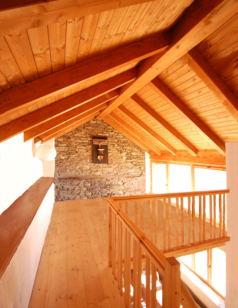 Ejemplo de dormitorio tipo loft rural de tamaño medio con paredes blancas, suelo de madera clara y suelo naranja