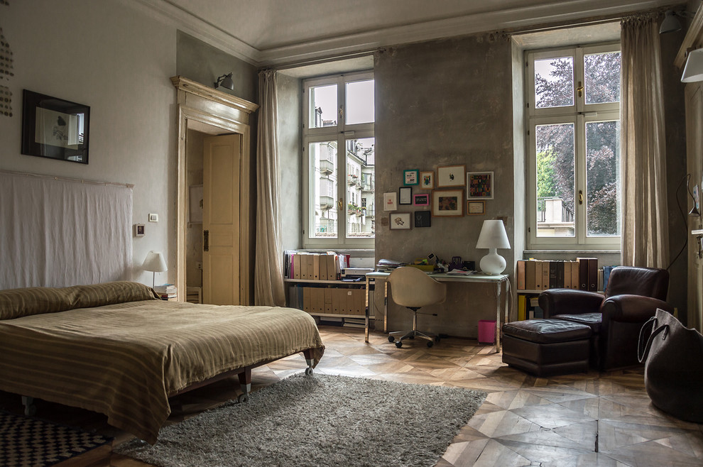 This is an example of an urban grey and brown bedroom in Turin with grey walls, medium hardwood flooring and brown floors.