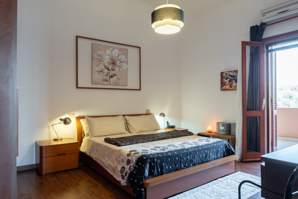 Aménagement d'une chambre contemporaine avec un mur blanc, un sol en bois brun et un sol marron.