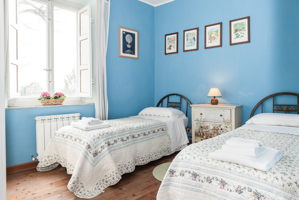 Foto di una camera degli ospiti mediterranea con pareti blu, pavimento in legno massello medio e pavimento marrone