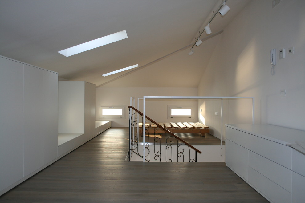 Exemple d'une chambre mansardée ou avec mezzanine tendance de taille moyenne avec un mur blanc, un sol en bois brun et un sol marron.
