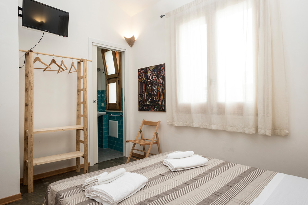 Свежая идея для дизайна: маленькая гостевая спальня (комната для гостей) в средиземноморском стиле с белыми стенами, бетонным полом и серым полом для на участке и в саду - отличное фото интерьера