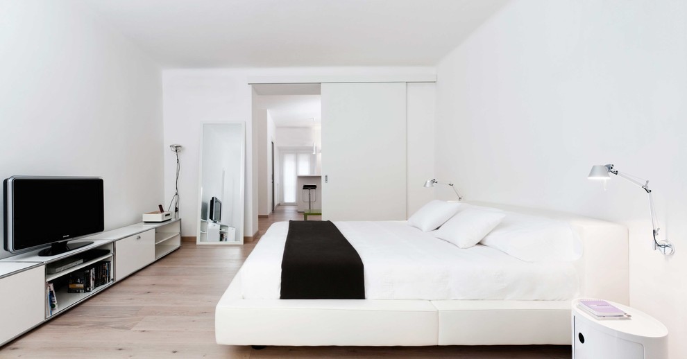 Imagen de dormitorio principal actual de tamaño medio con paredes blancas y suelo de madera clara