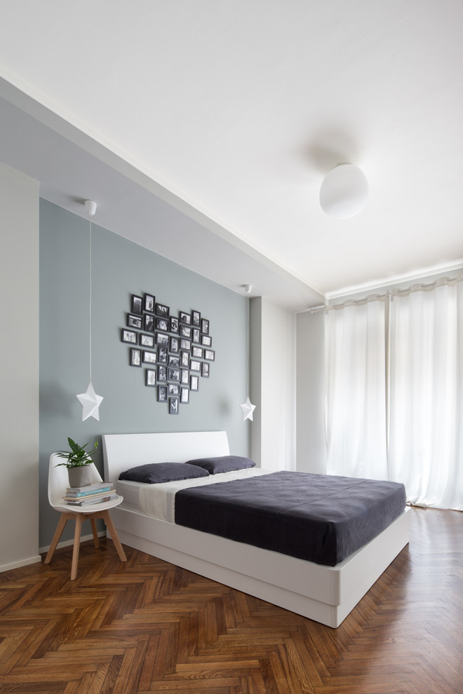 Diseño de dormitorio principal actual de tamaño medio sin chimenea con suelo de madera en tonos medios, paredes multicolor y suelo marrón
