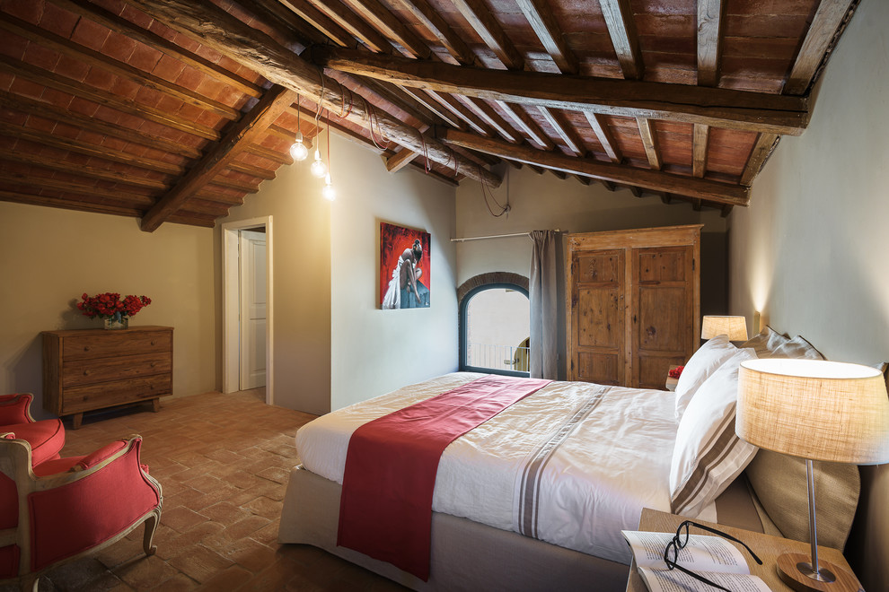Ejemplo de dormitorio principal de estilo de casa de campo grande sin chimenea con paredes beige, suelo de baldosas de terracota y suelo rojo