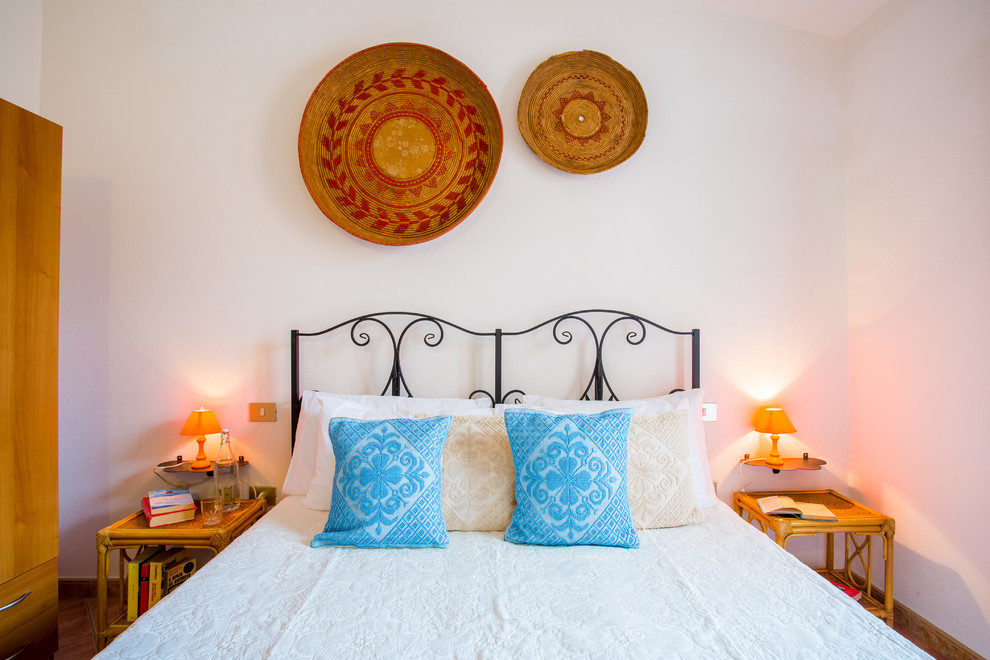 На фото: гостевая спальня среднего размера, (комната для гостей) в средиземноморском стиле с белыми стенами, полом из керамической плитки и коричневым полом с