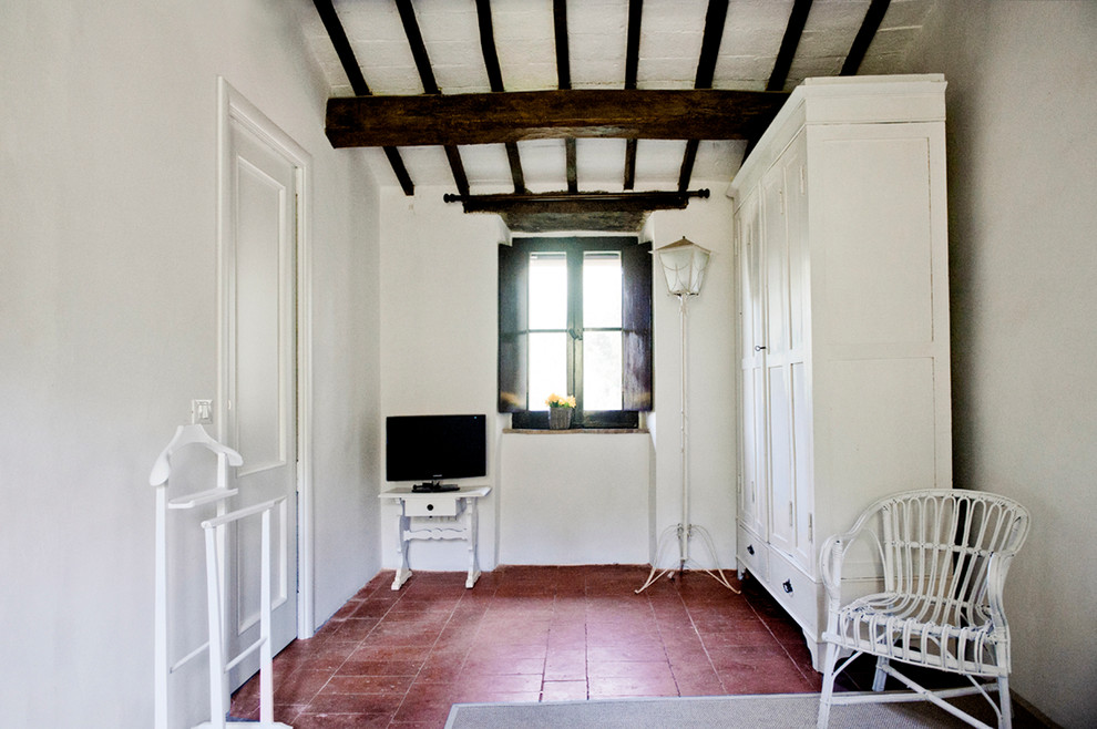 Bild på ett mellanstort lantligt gästrum, med vita väggar, klinkergolv i terrakotta och brunt golv
