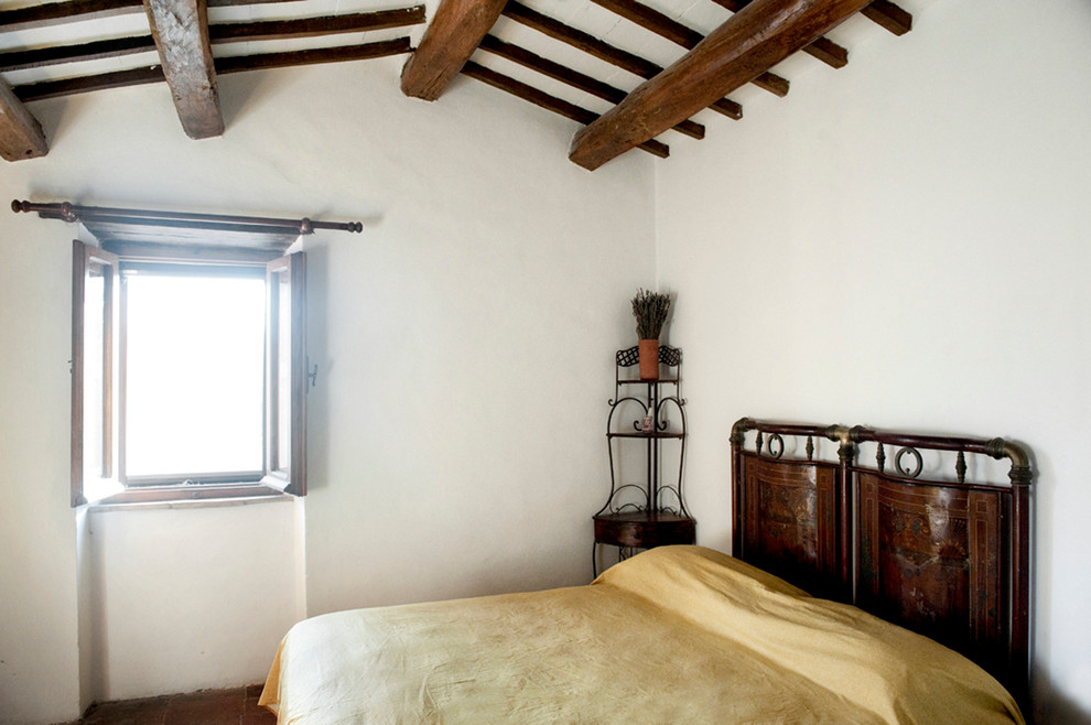 Exemple d'une chambre d'amis nature de taille moyenne avec un mur blanc, tomettes au sol et un sol marron.