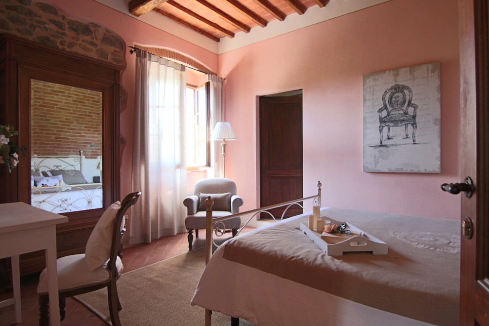 Inredning av ett lantligt mellanstort sovrum, med rosa väggar, klinkergolv i terrakotta och brunt golv