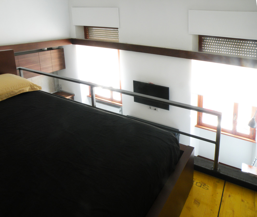 Esempio di una piccola camera da letto stile loft industriale con pareti bianche, pavimento in legno verniciato e pavimento giallo