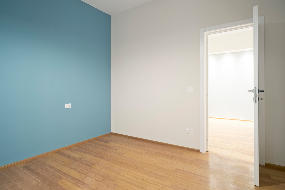 Immagine di una piccola camera matrimoniale design con pavimento in bambù, pavimento marrone e pareti blu