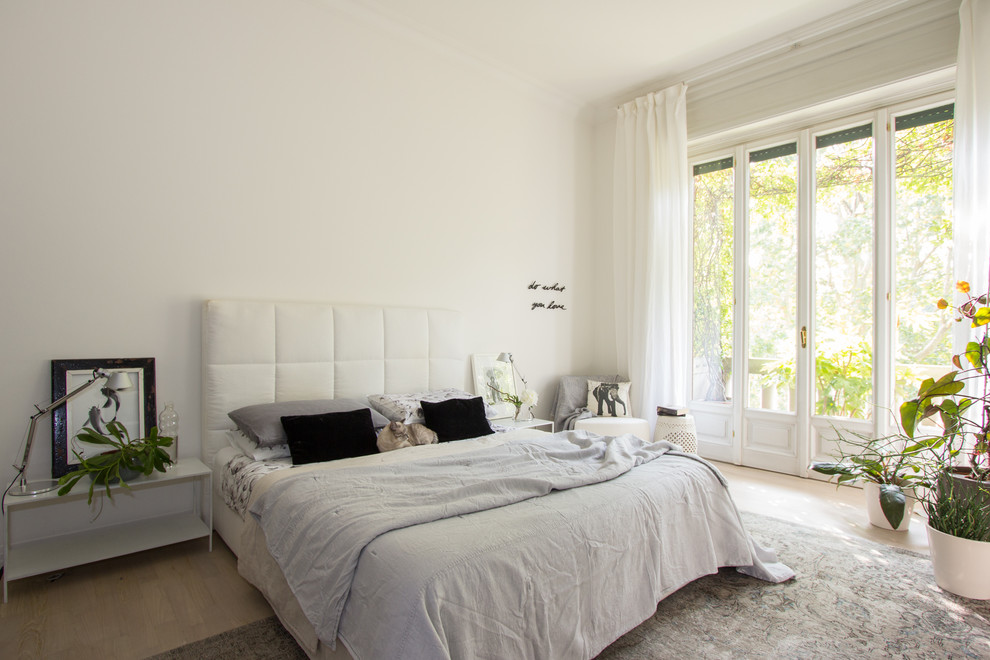 Inspiration for a scandi master bedroom in Milan with white walls, light hardwood flooring and beige floors.