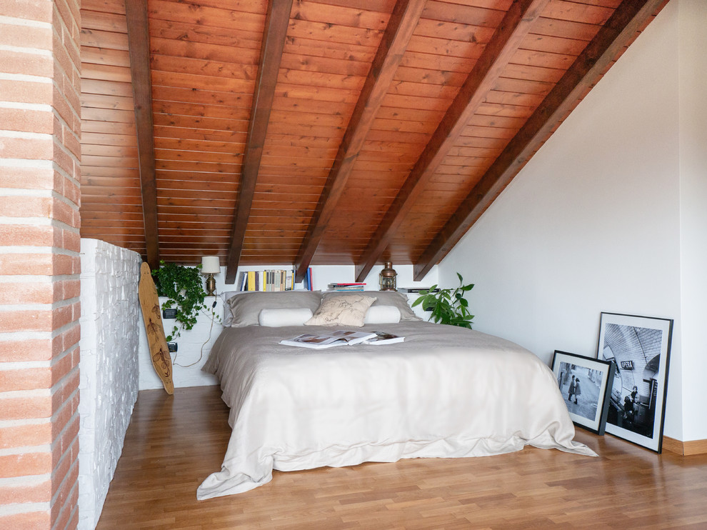 Large scandinavian mezzanine bedroom in Milan with white walls, light hardwood flooring and beige floors.