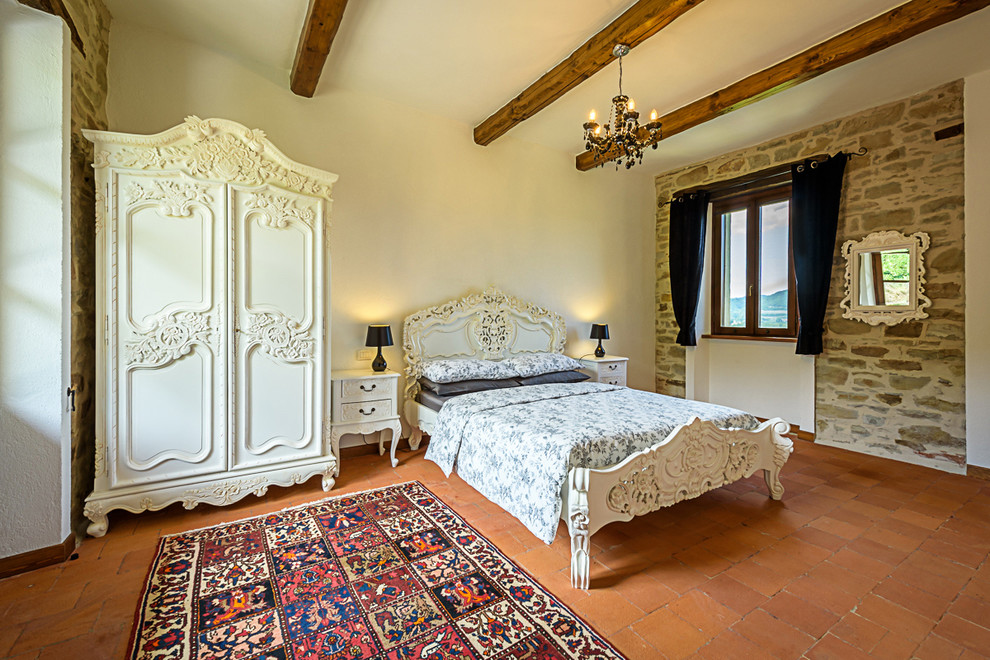 Ejemplo de dormitorio principal tradicional grande con paredes blancas y suelo de baldosas de terracota