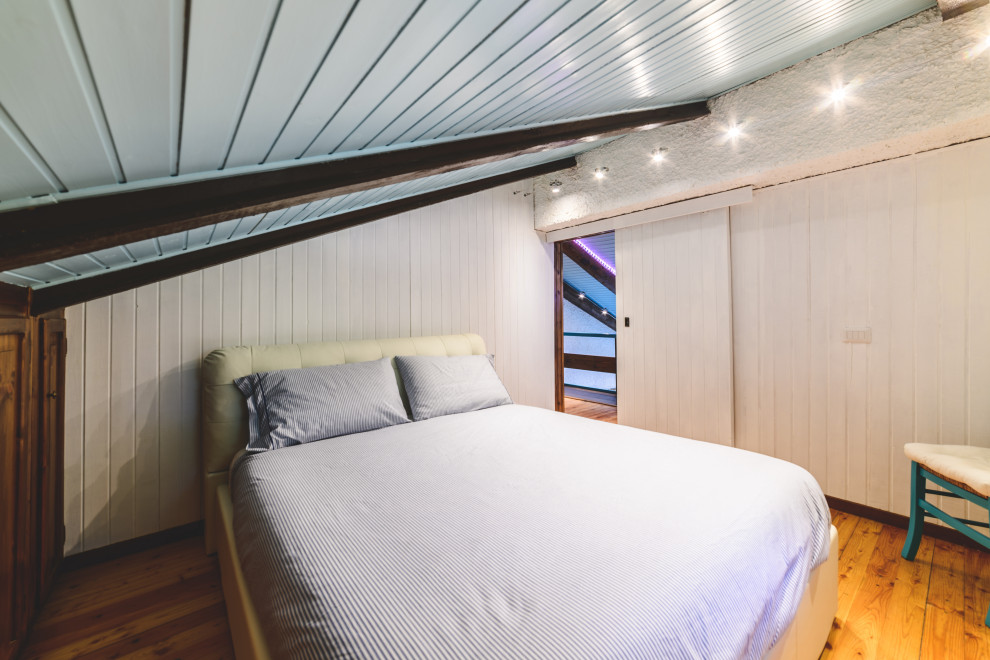 Foto de dormitorio principal moderno pequeño sin chimenea con paredes blancas, suelo de madera clara y suelo marrón