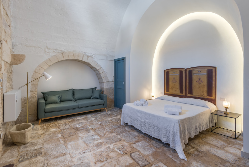 Идея дизайна: большая хозяйская спальня в средиземноморском стиле с белыми стенами, полом из известняка и бежевым полом