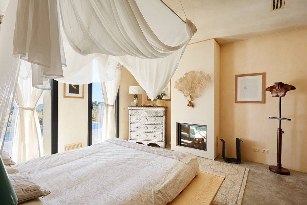 Идея дизайна: хозяйская спальня в морском стиле с бежевыми стенами, бетонным полом, стандартным камином и серым полом