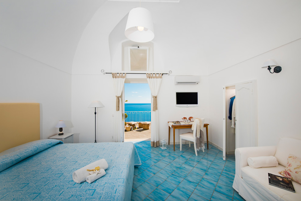 На фото: хозяйская спальня среднего размера в морском стиле с белыми стенами, полом из терракотовой плитки, бирюзовым полом и сводчатым потолком с