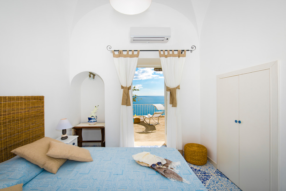 Cette photo montre une chambre parentale beige et blanche méditerranéenne de taille moyenne avec un mur blanc, tomettes au sol, un sol multicolore et un plafond voûté.