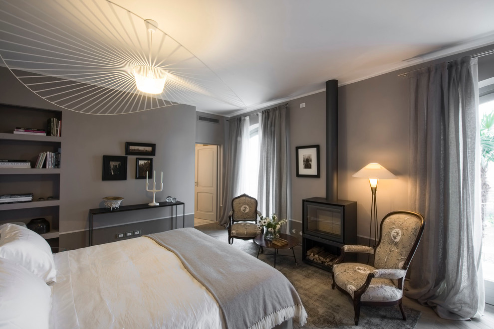 Пример оригинального дизайна: огромная хозяйская спальня в современном стиле с серыми стенами, деревянным полом и печью-буржуйкой