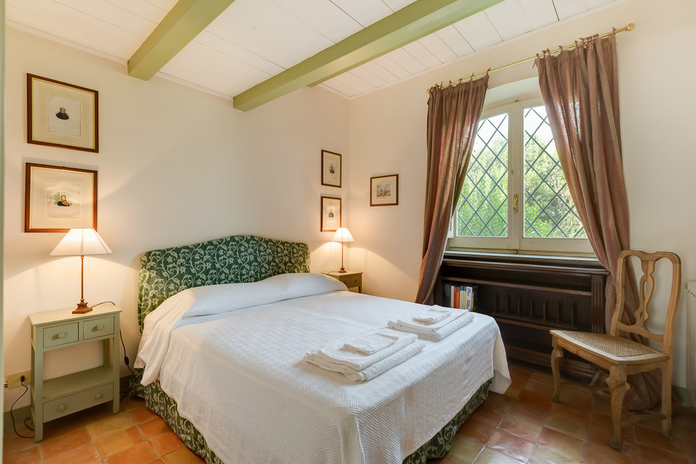 Foto di una camera degli ospiti country con pareti bianche e pavimento in terracotta