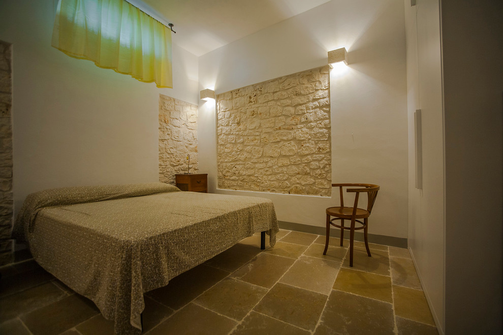 Imagen de habitación de invitados campestre de tamaño medio con paredes blancas, suelo de piedra caliza y suelo gris