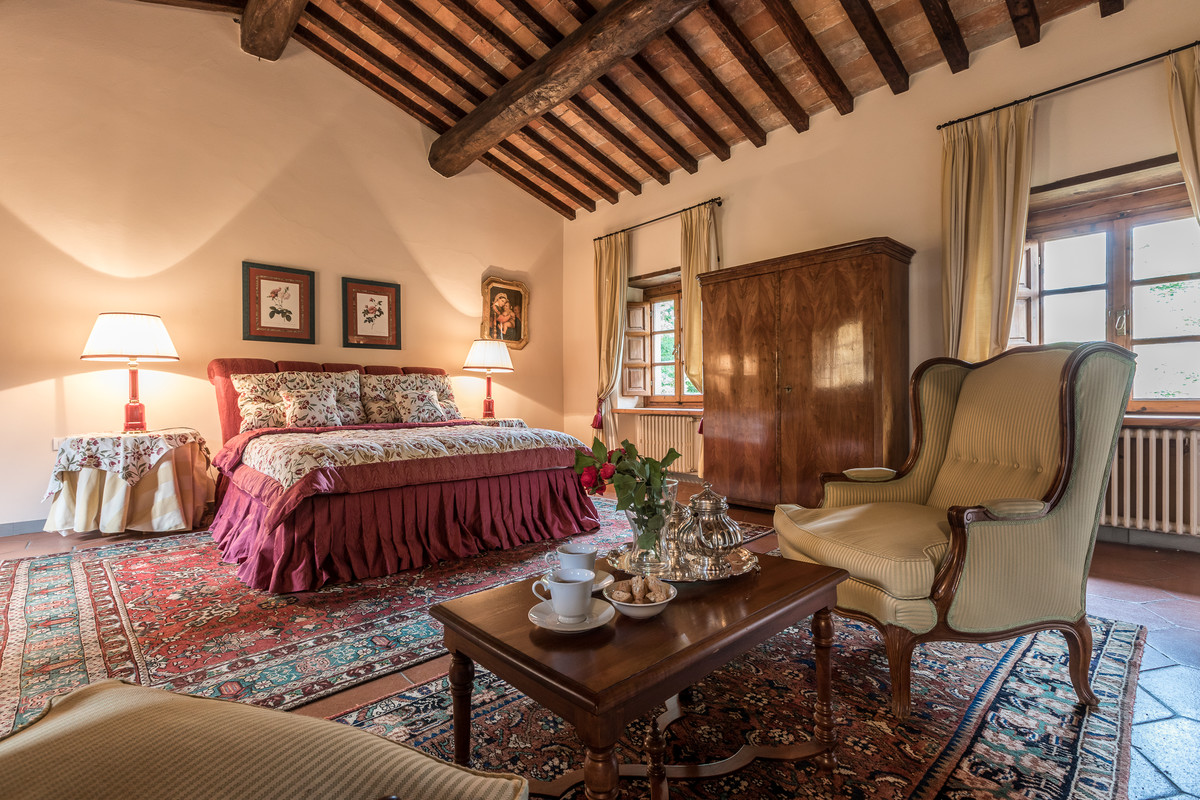 Huge cottage master terra-cotta tile and red floor bedroom photo in Florence with beige walls, a standard fireplace and a stone fireplace