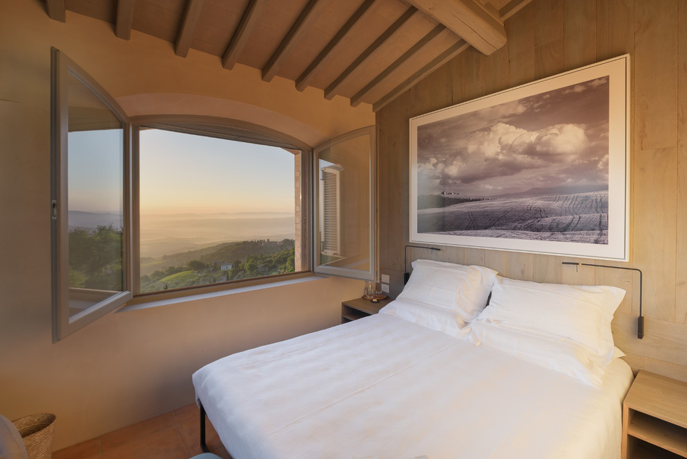 На фото: спальня в средиземноморском стиле с бежевыми стенами, полом из терракотовой плитки и коричневым полом