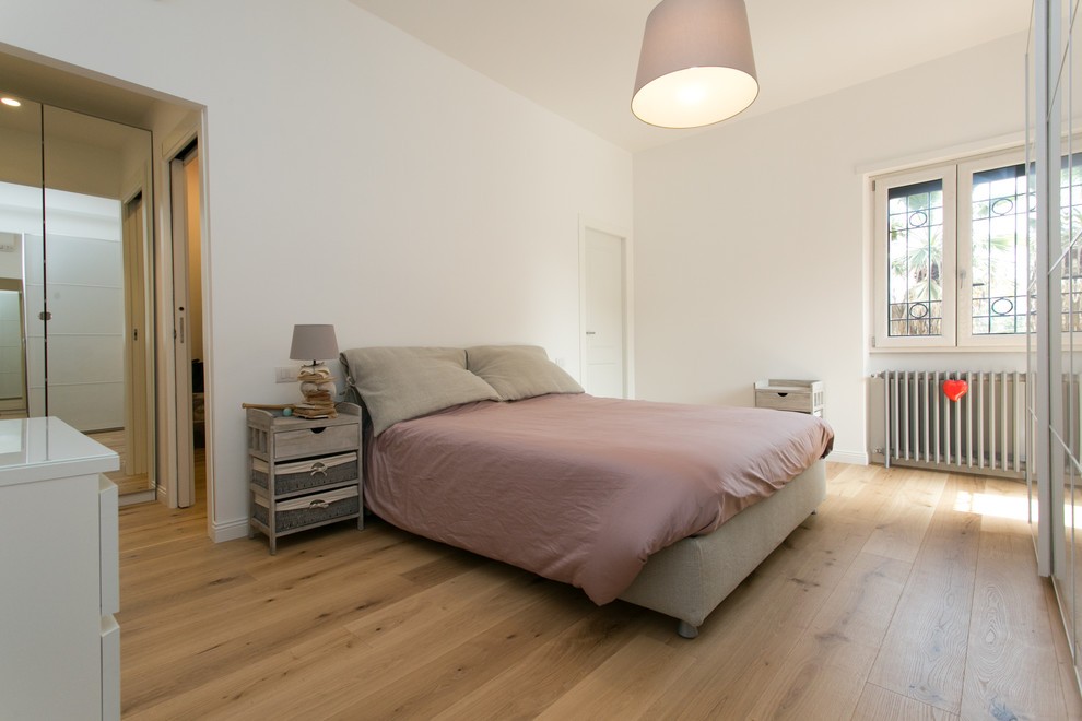Photo of a large contemporary master bedroom in Rome with white walls and medium hardwood flooring.