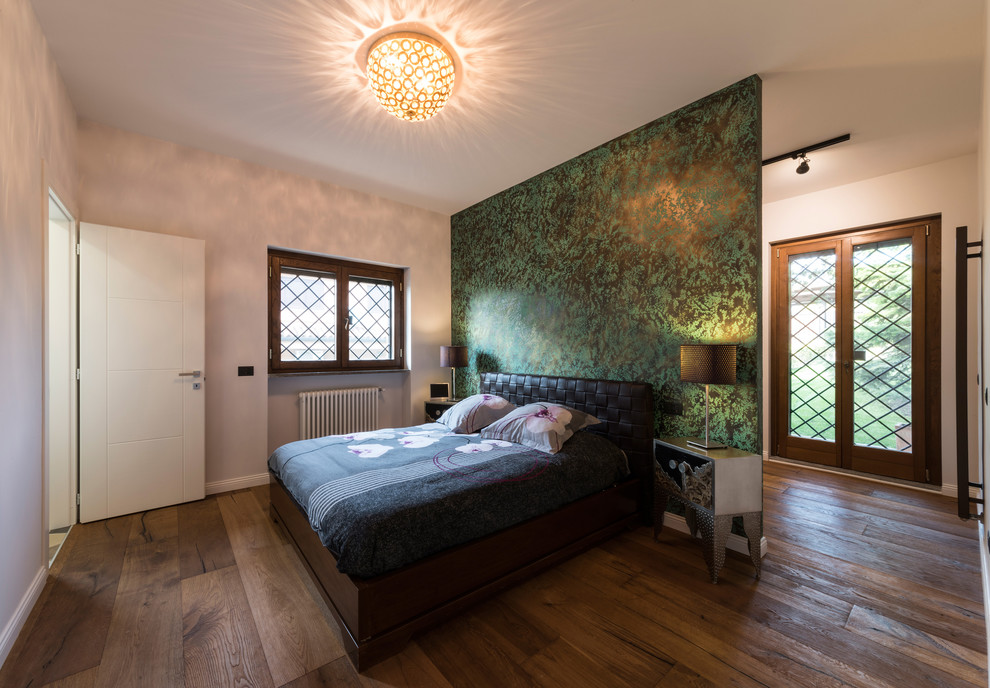 Cette image montre une grande chambre parentale design avec un sol en bois brun, un mur vert et un sol marron.