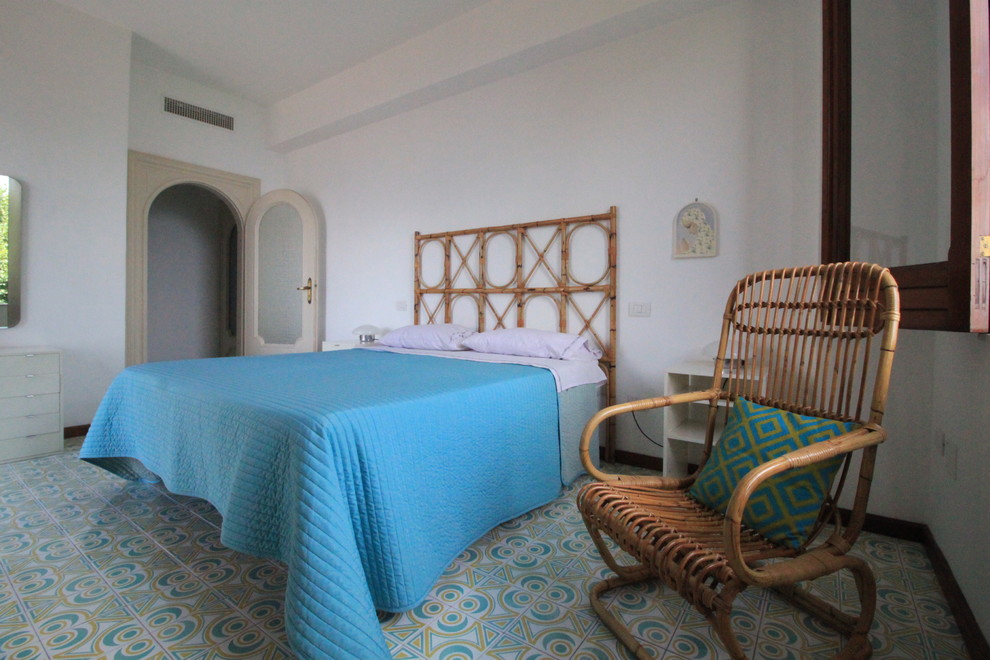 Immagine di una piccola camera degli ospiti tropicale con pareti bianche, pavimento con piastrelle in ceramica e pavimento multicolore