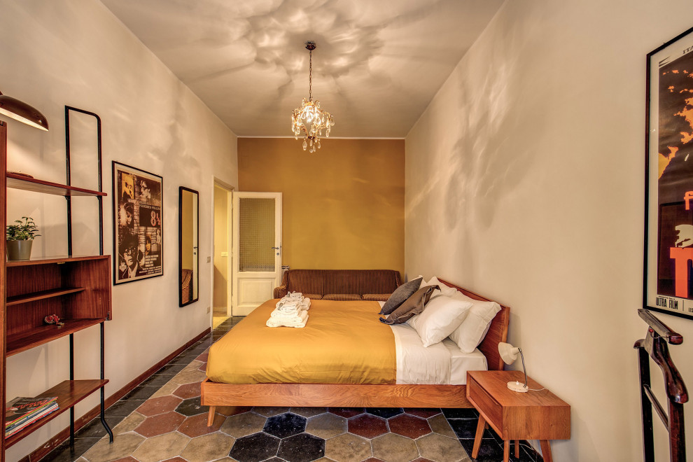 Immagine di una camera matrimoniale minimalista di medie dimensioni con pareti gialle, pavimento in cemento e pavimento multicolore