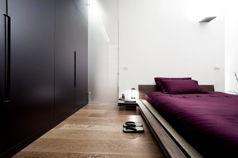 Inspiration för moderna sovrum, med vita väggar och mellanmörkt trägolv