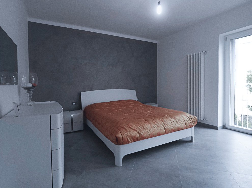 Imagen de dormitorio principal actual de tamaño medio sin chimenea con paredes blancas, suelo de baldosas de porcelana y suelo gris