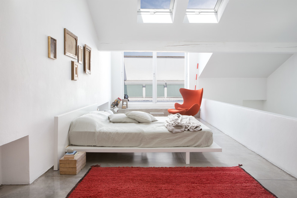 На фото: большая хозяйская спальня на мансарде в современном стиле с белыми стенами и бетонным полом с