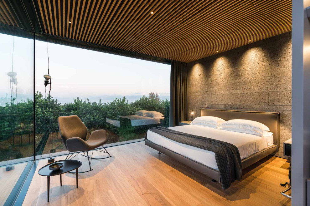 Modelo de dormitorio minimalista con paredes grises, suelo de madera en tonos medios y suelo marrón